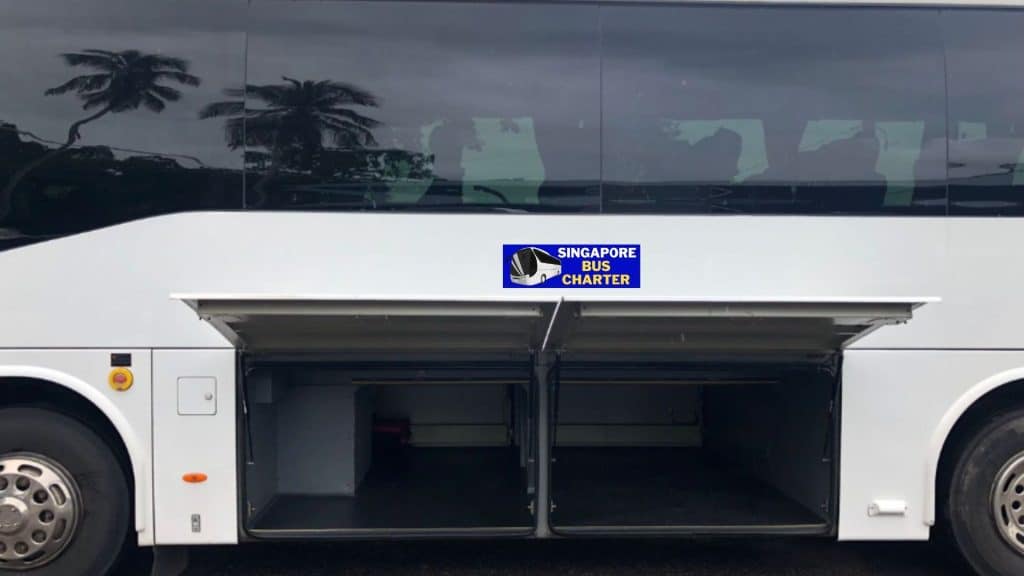 A detailed view of a Singapore bus charter vehicle with open luggage compartments.